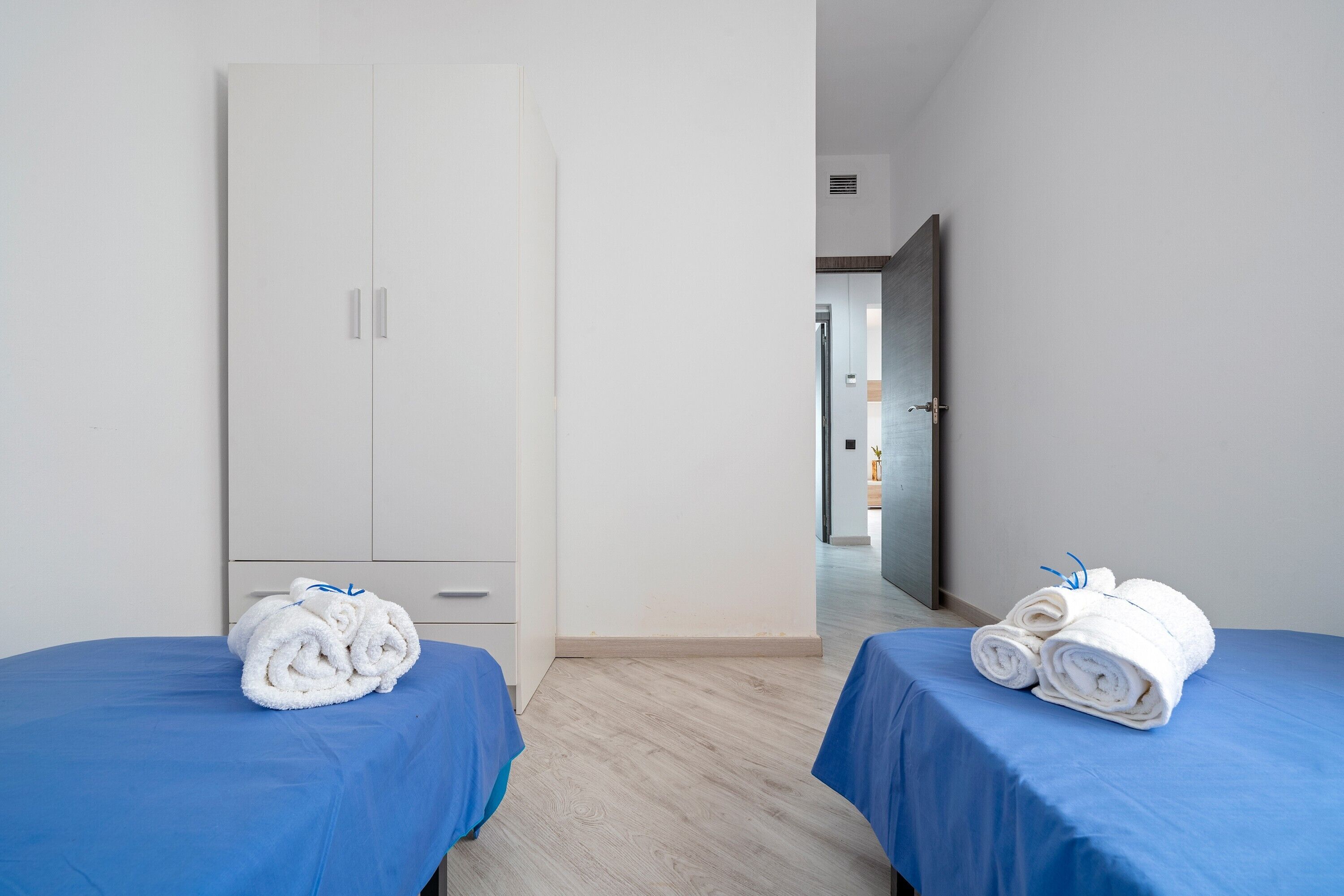 Une chambre d’hôtel avec deux lits, une armoire et une vue sur une autre chambre.
