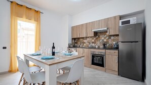 A modern kitchen with a dining table, chairs, a refrigerator, and an oven.