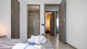 Una habitación de hotel con una cama, dos puertas que dan a otras habitaciones y un baño visible.
