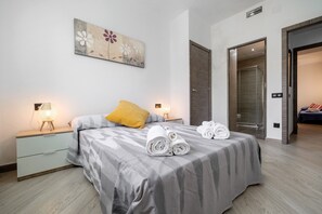Ein Schlafzimmer mit einem Bett, zwei Nachttischen, einer Ablagefläche, einem Gemälde und einem Duschbereich.