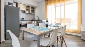 A modern kitchen with a refrigerator, oven, and microwave. There is a dining table with chairs and a window with curtains. - Holiday Apartment "Cambrils Turistic Atico" with Private Terrace & Wi-Fi (Cambrils)