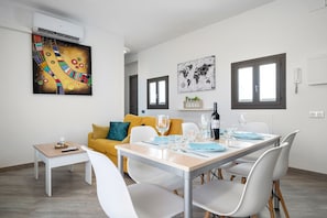 En moderne stue med spiseplads, sofa, sofabord og et verdenskort som kunstværk.