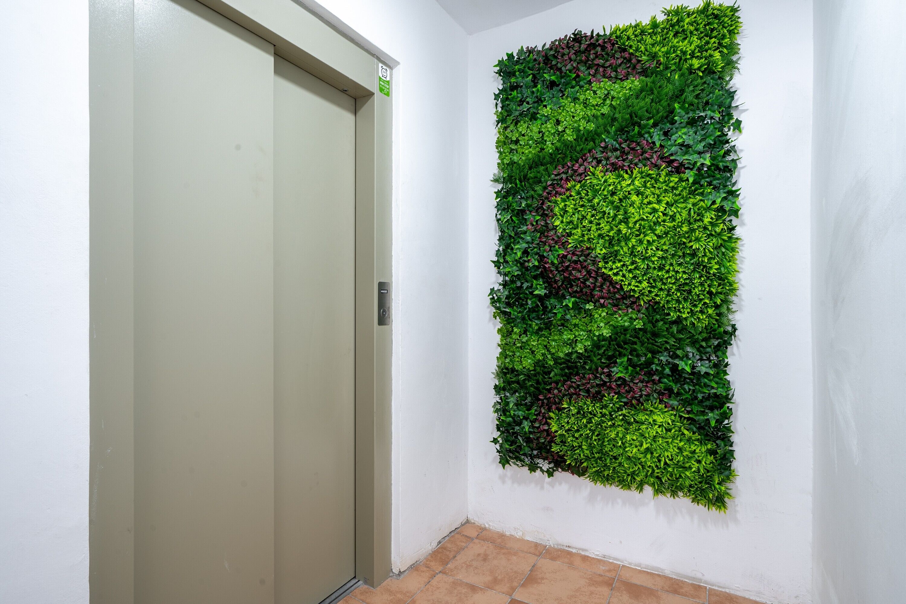 A hallway with a door and a vertical garden wall.