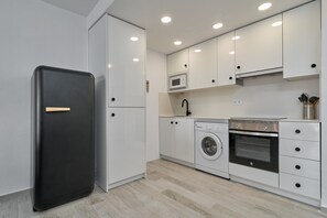 Una cocina compacta con un refrigerador negro, lavadora, microondas y horno.