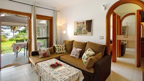 A living room with a sofa, a coffee table, and a dining area with a table and chairs. - Vacation Apartment 'Residencial Sol Suite 2' with Sea View, Shared Pool and Wi-Fi (Puerto Rico)