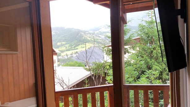 Un balcón de madera con vista a un paisaje verde y colinas distantes.