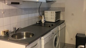 Cocina compacta con un lavamanos, un microondas y una lavadora.