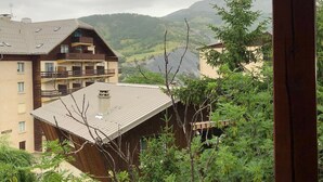 Un lodge de montaña con fachada de madera, varios balcones y vistas a un valle y montañas.