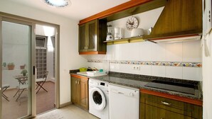A compact kitchen with a washing machine, a coffee maker, and a microwave. - Vacation Home 'Residencial Sol Suite' with Private Terrace, Balcony and Wi-Fi (Telde, Gran Canaria)