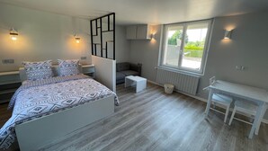 Een slaapkamer met een bed, een bureau, een stoel, een bank en een raam.
