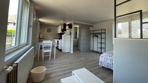 Een compact appartement in moderne stijl, met kitchenette, eethoek, bed en inbouwkast.
