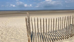 Een strand met een houten omheining en een heldere lucht.