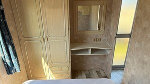 Un dormitorio con cama, armario, espejo y tragaluz.