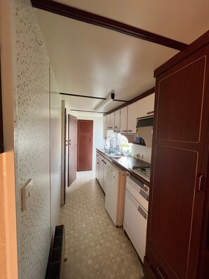 A narrow kitchen with a refrigerator, stove, and cabinets.
