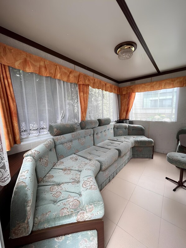 A sectional sofa with a floral pattern, a small round table, and a window with curtains.