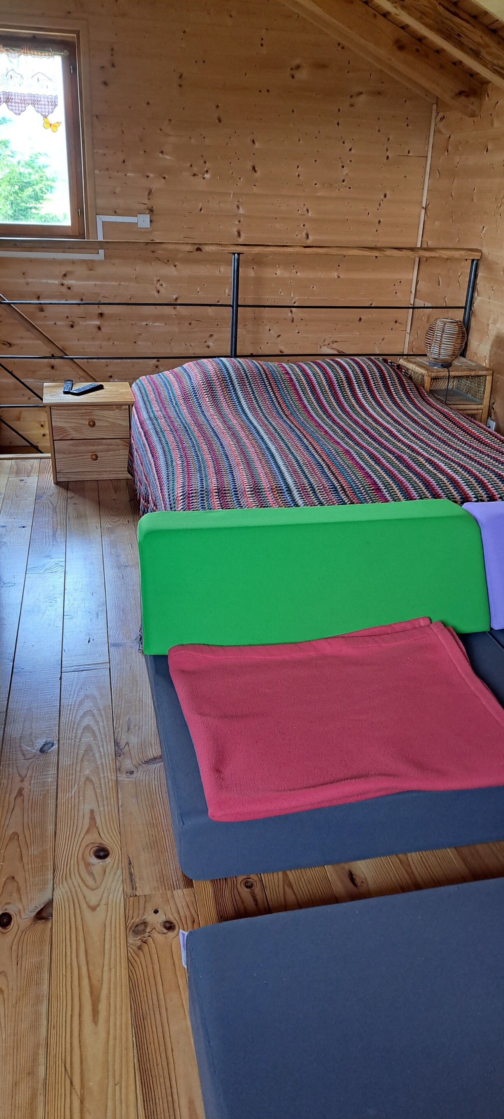Una habitación de cabaña de madera con una cama, una mesita de noche y una ventana.