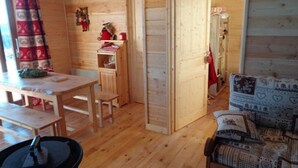 A wooden interior with a dining table, chairs, a sofa, and a small kitchen area.