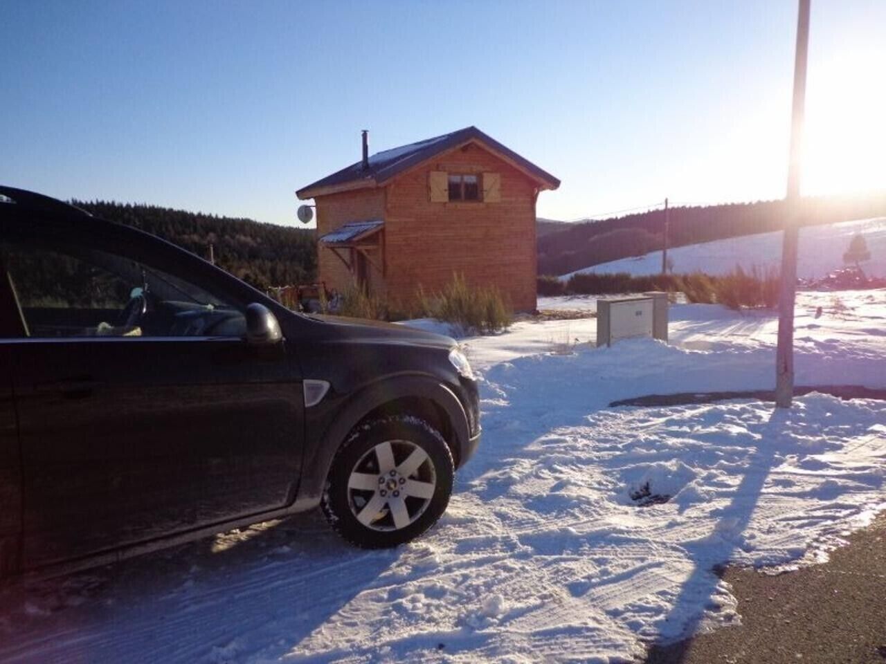 Et køretøj parkeret i et snækkedækket område med en lille murstensbygning i baggrunden.