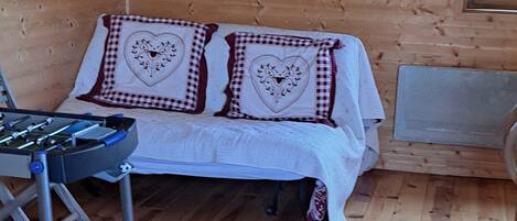 A cozy wooden room with a bed, a table, and a colorful blanket.