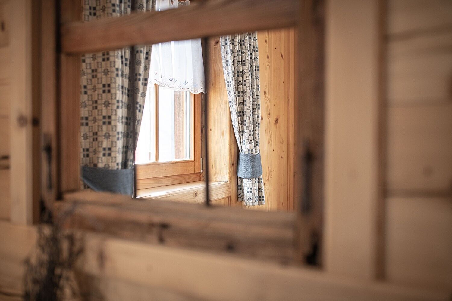 A window with patterned curtains and a wooden frame.