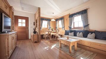 A wooden interior with a TV, dining table, and sofa.