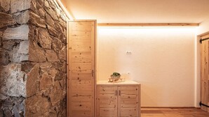 Une pièce avec un mur en pierre, un meuble en bois et une petite table sur laquelle est posée une plante.