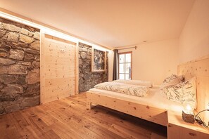 A bedroom with a wooden bed, stone walls, and a window.