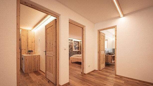 Un couloir doté de planchers en bois et de portes donnant sur une chambre et une salle de bain.