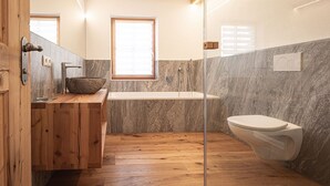 Une salle de bain moderne avec un meuble-lavabo en bois, une baignoire sur pieds et des toilettes.