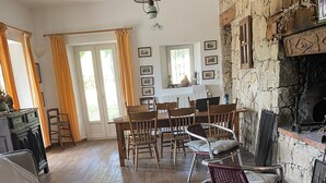Ruokailutila, jossa on kiviseinä, puuhuonekalut ja takka.