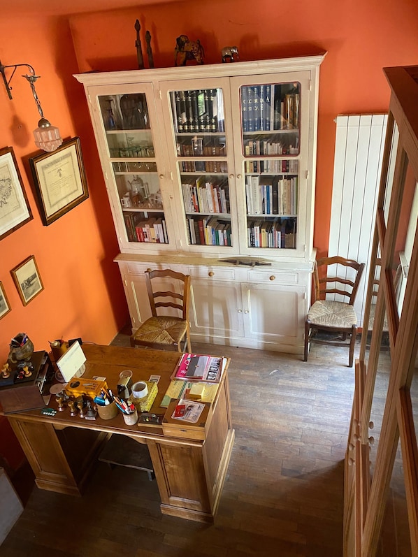 A room with a wooden desk, chairs, a bookshelf, and framed certificates on the wall.
