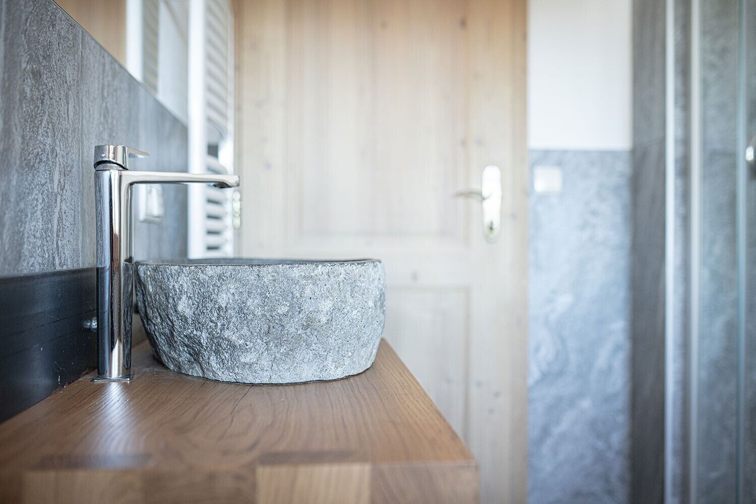 Un bagno con un mobile lavabo in legno, un lavandino in pietra e un rubinetto cromato.