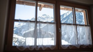 Een uitzicht op besneeuwde bergen vanuit een raam, met een gebouw.
