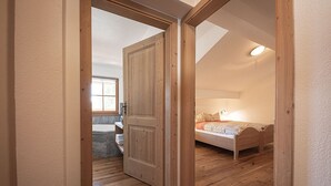 Een slaapkamer met een houten bed, een raam en een badkamer met bad.
