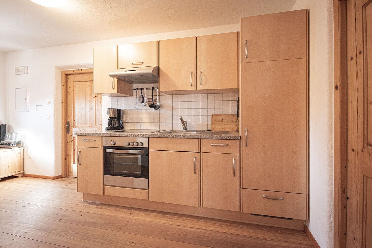 Una cocina con armarios de madera, horno empotrado y cafetera.