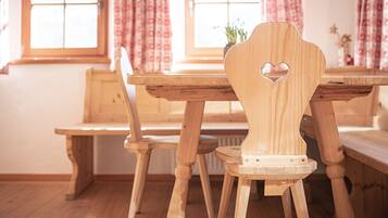 Un tavolo da pranzo in legno con un'apertura a forma di cuore sullo schienale, abbinato a sedie e una panca coordinati.