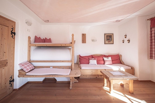 A room with bunk beds, a sofa, and a small table.