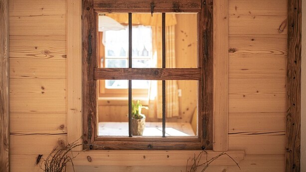 A wooden cabin interior with a window, wooden walls, and a view of a house outside. - Holiday Apartment "Himmelschlüssel" with Mountain View, 2 Private Terraces & Wi-Fi (Acereto)