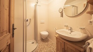 A bathroom with a shower, toilet, sink, and wooden cabinets. - Holiday Apartment "Himmelschlüssel" with Mountain View, 2 Private Terraces & Wi-Fi (Acereto)