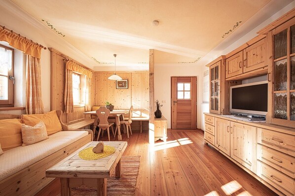 A cozy wooden interior with a sofa, dining table, and cabinets.