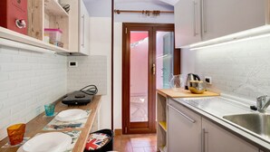 A compact kitchen with white brick walls, a wooden countertop, a sink, and a door leading to an outdoor area. - Holiday Apartment "Casa Scotland" with Sea View, Private Terrace, and Wi-Fi (Ventimiglia)