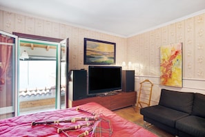Une pièce comprenant un lit, un canapé, un téléviseur et un tableau accroché au mur.