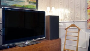 A flat-screen TV on a wooden cabinet, a speaker, and a wooden ladder. - Holiday Apartment "Casa Scotland" with Sea View, Private Terrace, and Wi-Fi (Ventimiglia)