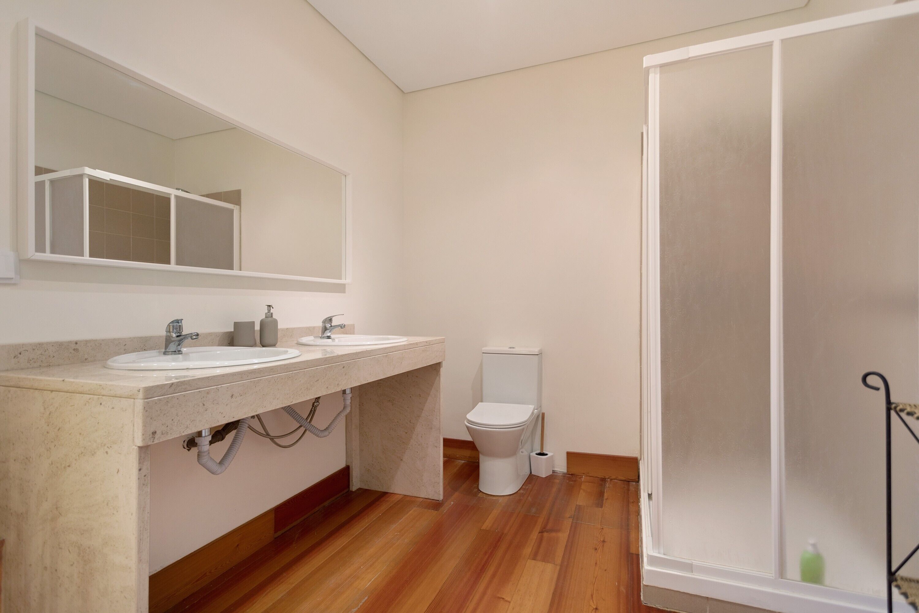 Un baño con lavamanos doble, inodoro y zona de ducha.