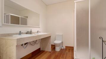 Un baño con lavamanos doble, inodoro y zona de ducha.