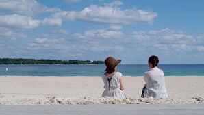 Two people on a beach with a clear sky and calm sea. - ASBO STAY HOTEL (Kin)