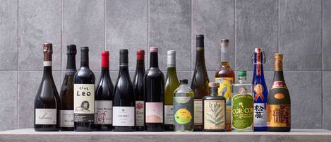 A selection of wine bottles on a wooden surface against a tiled wall.