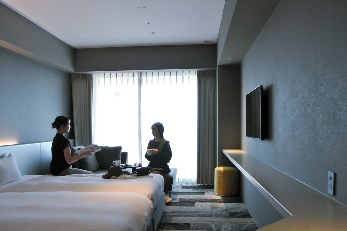 A modern hotel room with a large bed, a desk, and a television on the wall.