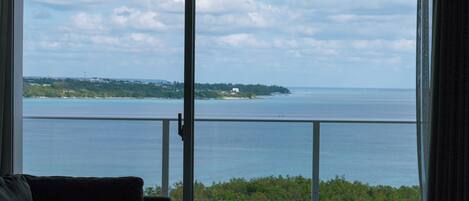 A room with a view of a large body of water, a balcony, and a couch.