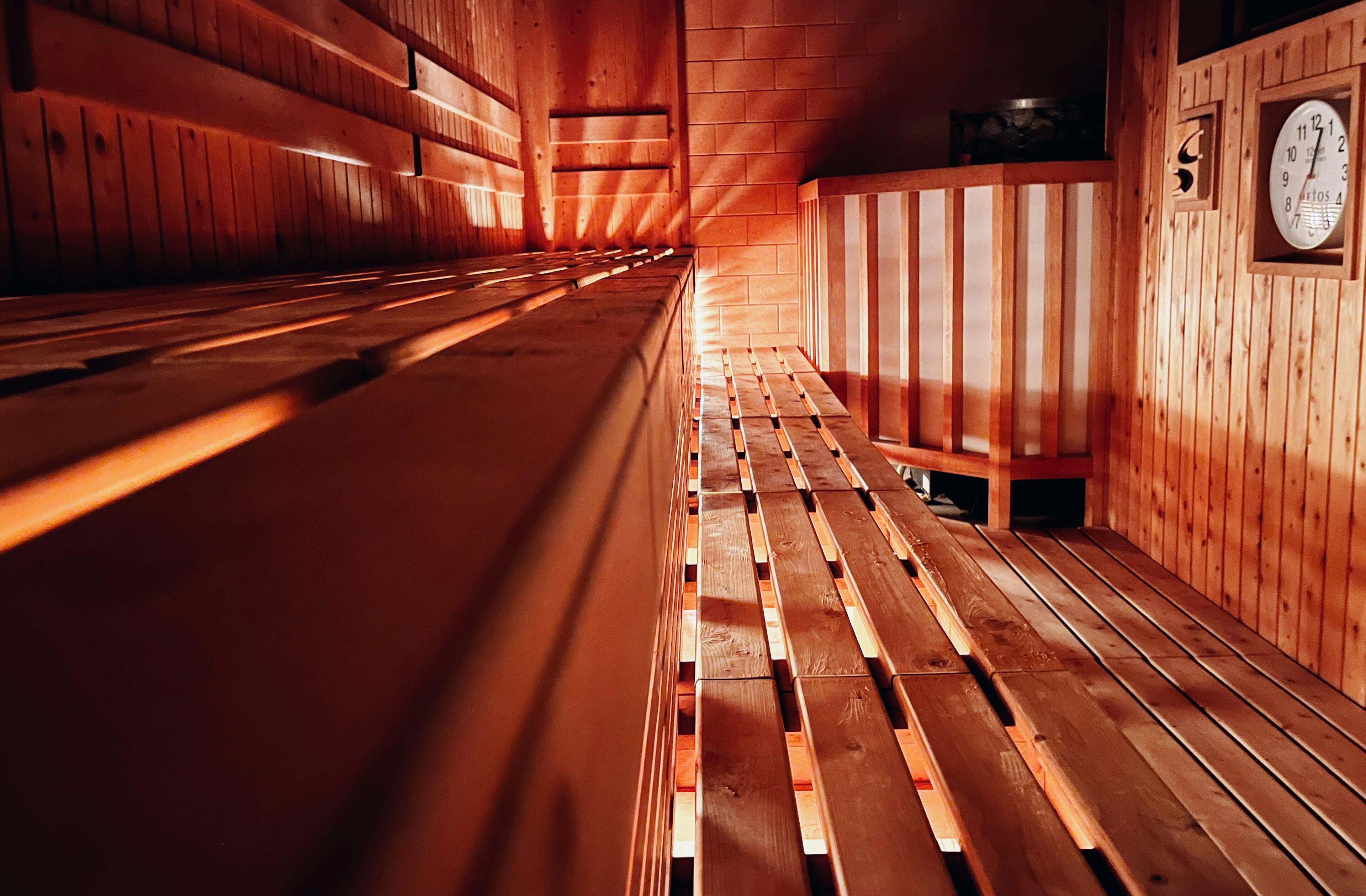 A sauna with wooden benches and a clock on the wall.